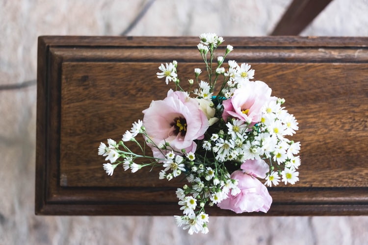 pink and white flowers on brown wooden casket