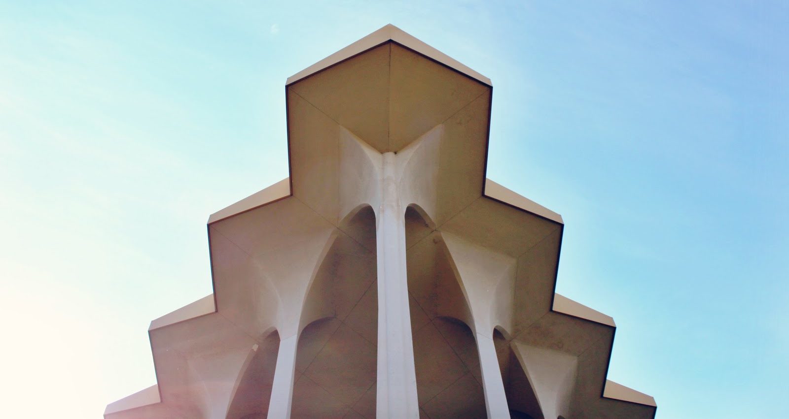 blue sky, church exterior with pillars, jagged shaped roof